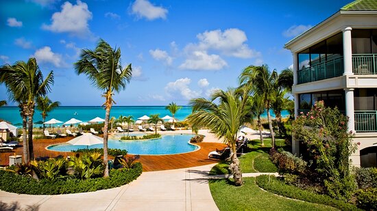 A sunny day at a beachfront hotel in the Turks and Caicos, with lush green landscaping and vibrant blue water