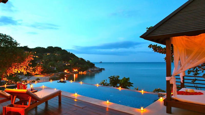 A honeymoon-style resort setting in Thailand with a private pool and illuminated deck overlooking the water