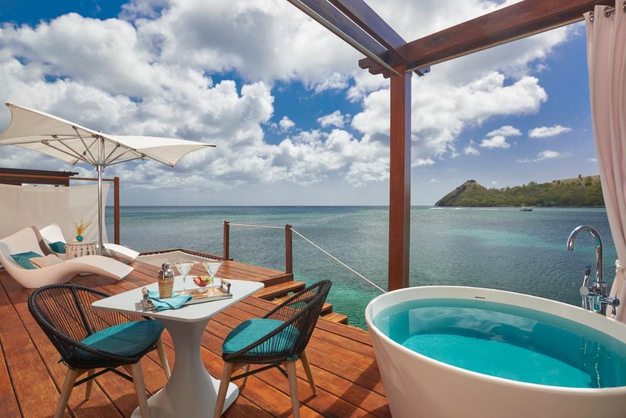 A private deck with a hammock and a white umbrella, showing the vast blue ocean under a partly cloudy sky