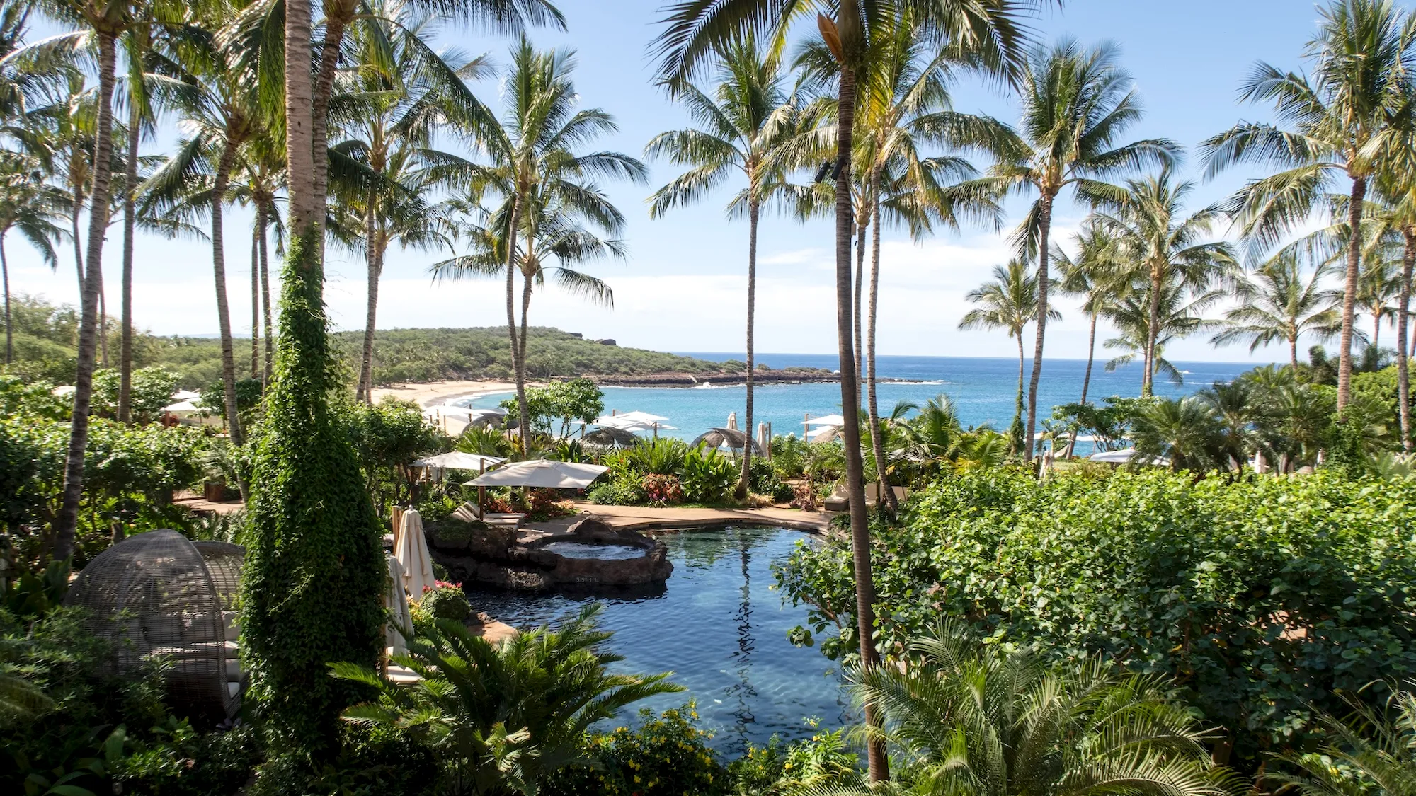 An inviting resort scene on Lanai, Hawaii, with a pool in the foreground and a calm ocean bay in the distance