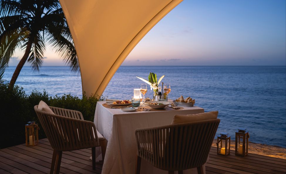 Romantic dinner for two on a wooden deck at sunset overlooking the ocean