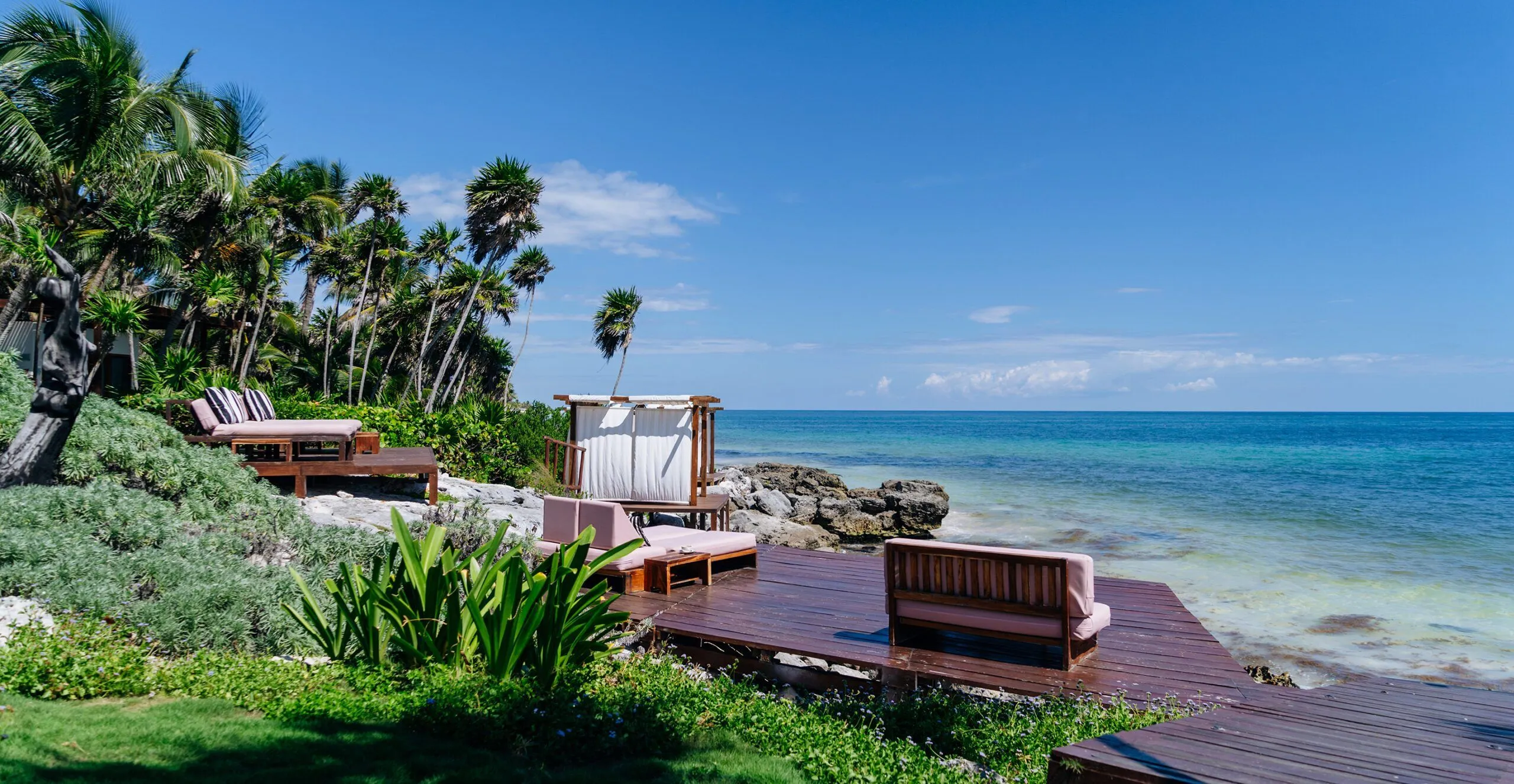 A sunny view of a Mexican resort's private oceanfront deck and natural stone shoreline